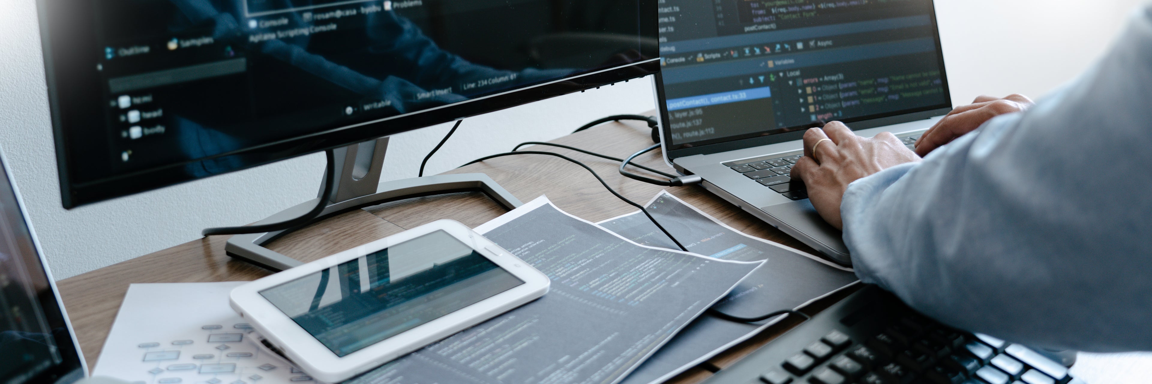 man inputting code on laptop desktop nearby and tablet